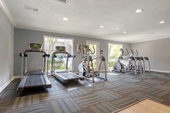 A gym with treadmills, elliptical machines, and stationary bikes